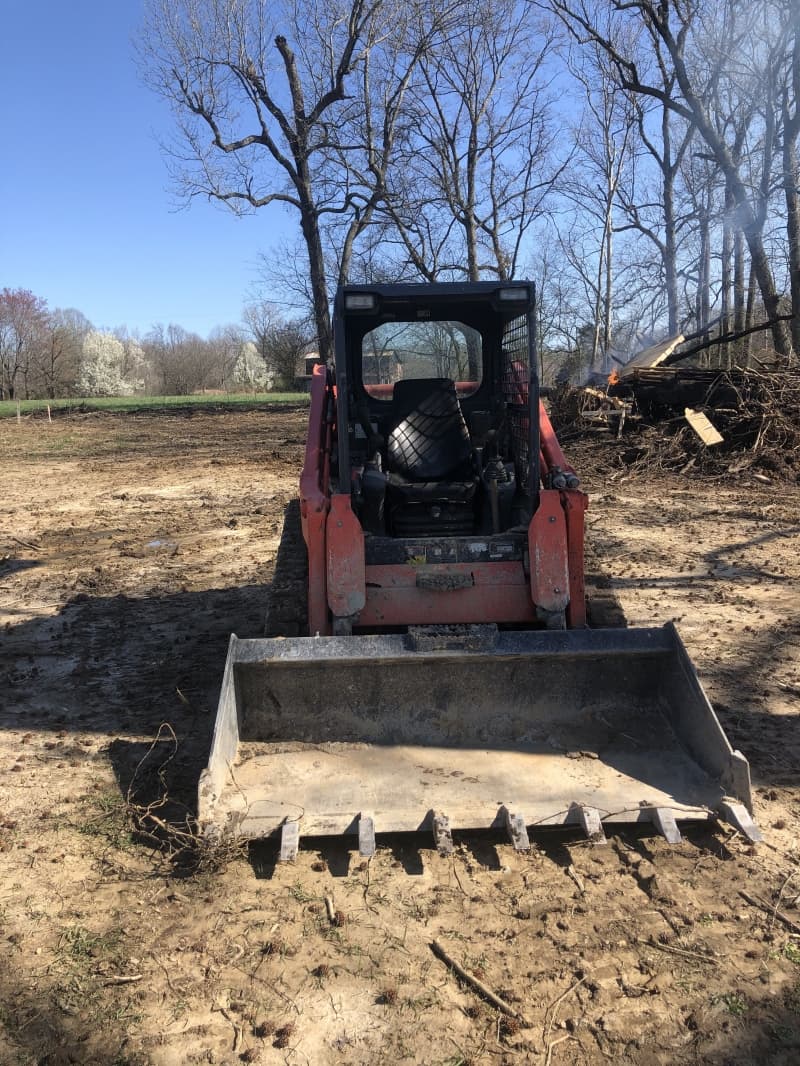 Kabota skid steer with tooth bucket and brush grabber